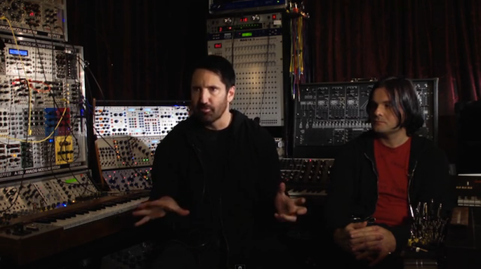 Trent Reznor and Alessandro Cortini sit in front of their big, weird synthesizer.